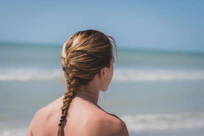 海边一位梳着辫子头发的妇女的后视图照片